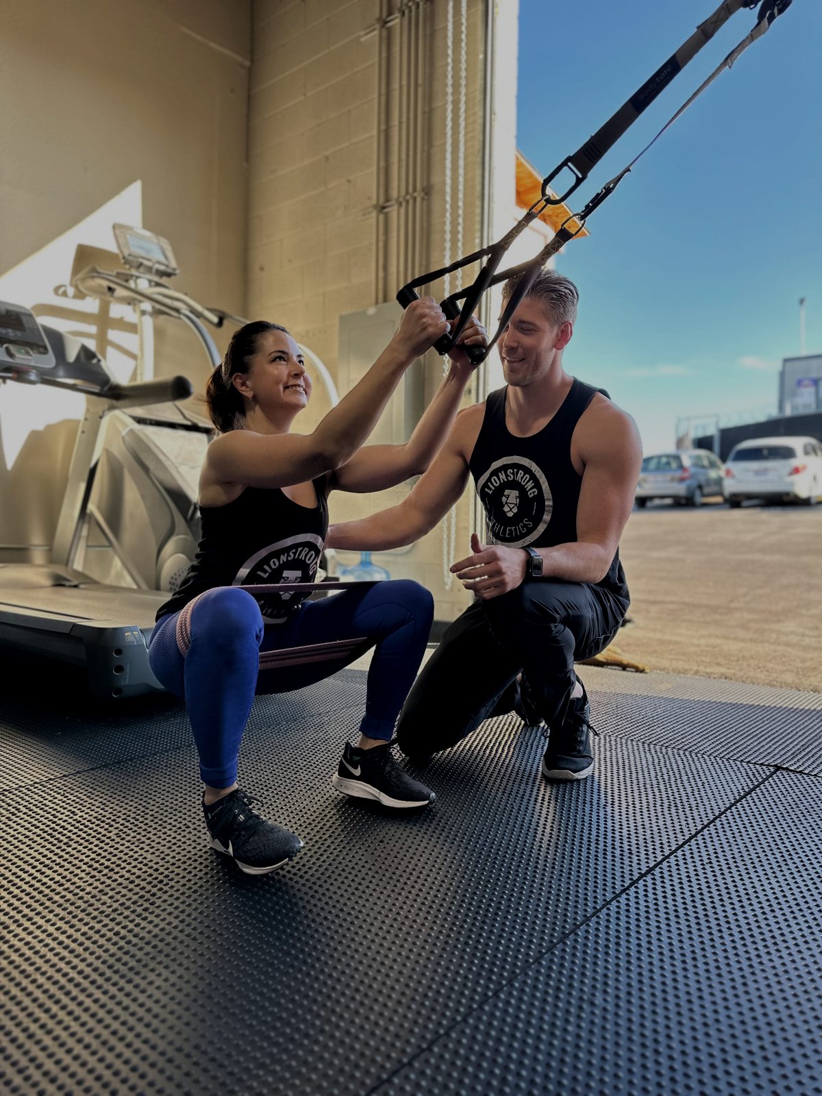 LionStrong coach guiding a client through a banded assisted squat outside the San Diego facility